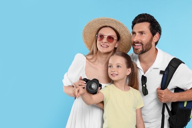 Photo of Happy family with camera on light blue background, space for text