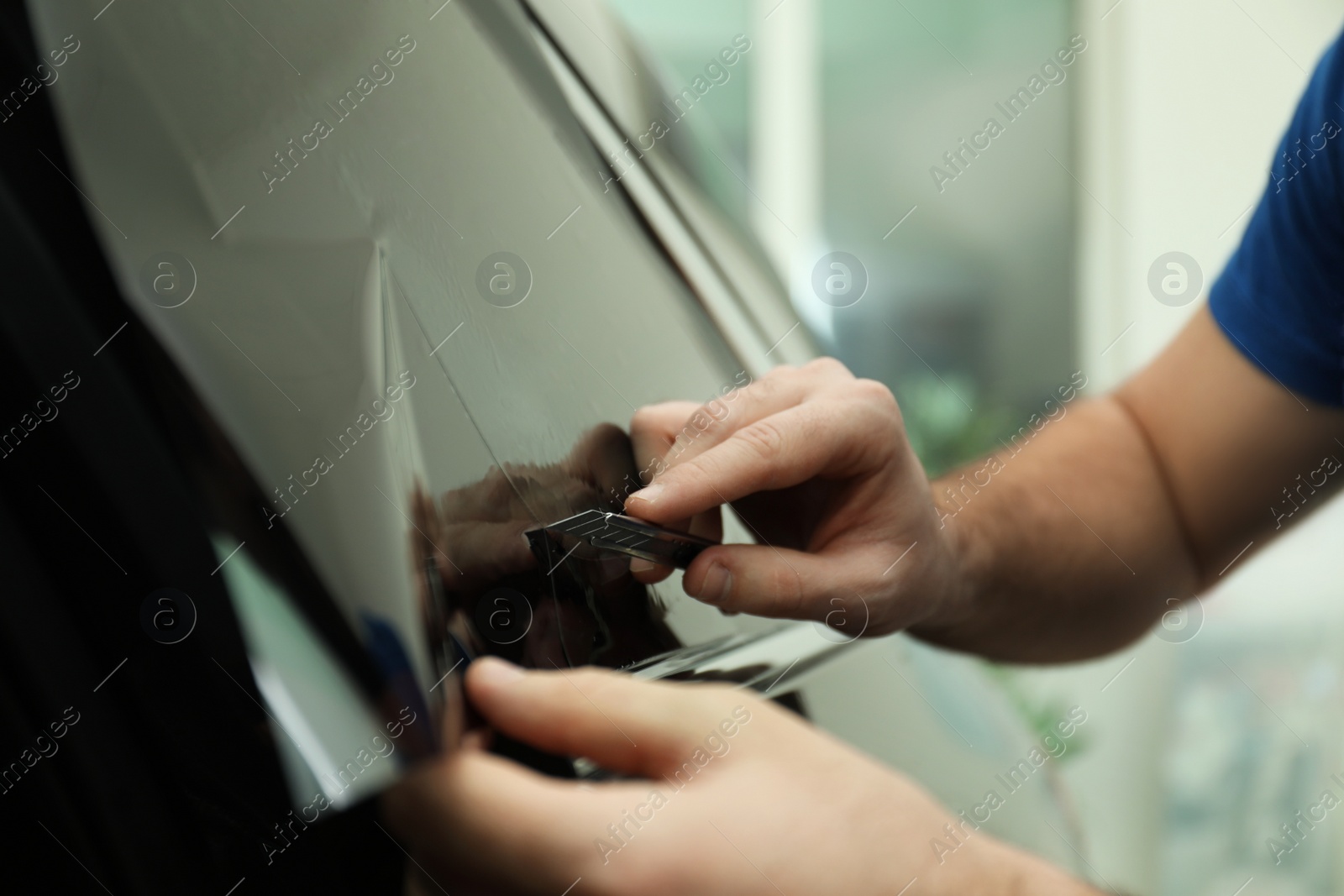 Photo of Worker tinting car window with foil in workshop, closeup