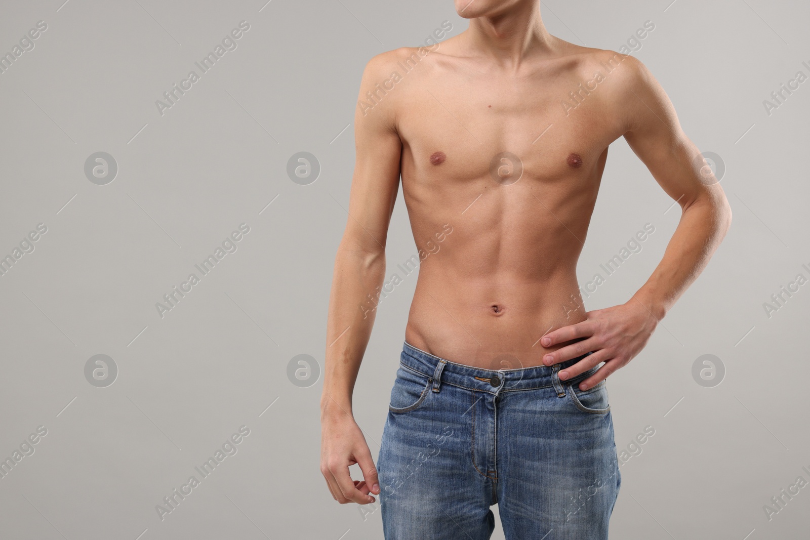 Photo of Shirtless man with slim body on grey background, closeup. Space for text