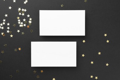 Photo of Blank business cards and confetti on black background, top view. Mockup for design