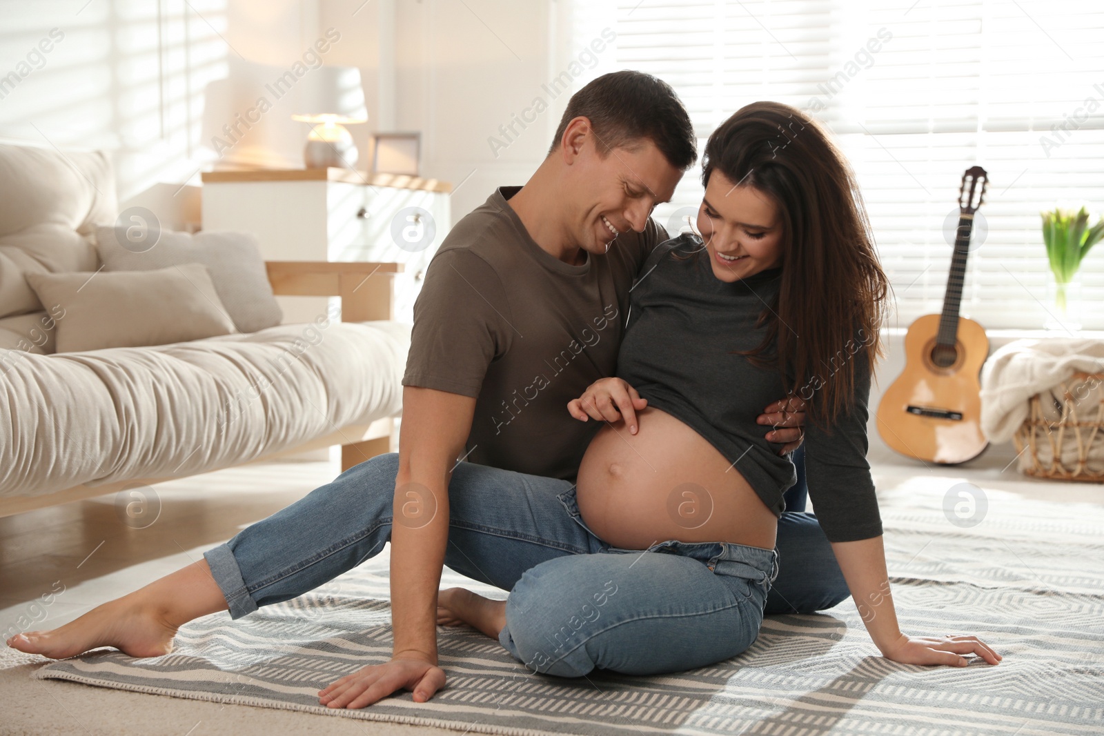 Photo of Young pregnant woman with her husband at home