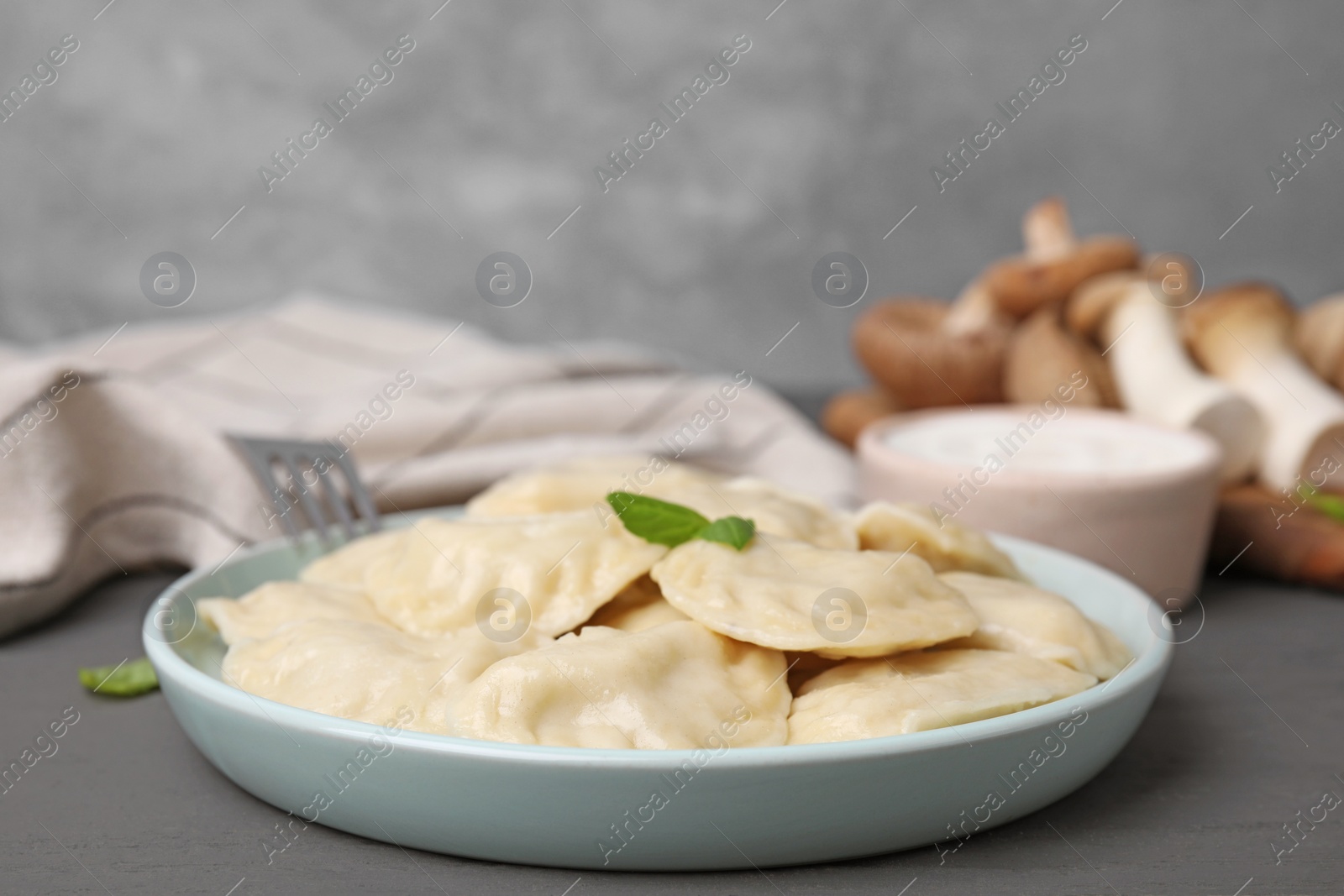 Photo of Plate of delicious dumplings (varenyky) on grey wooden table, closeup
