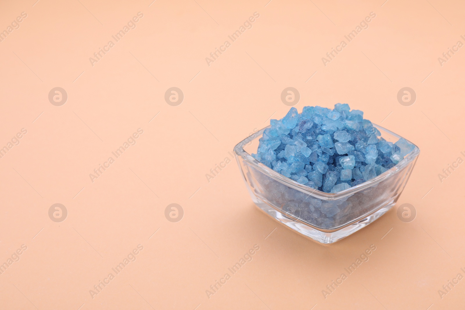 Photo of Bowl with blue sea salt on beige background, space for text