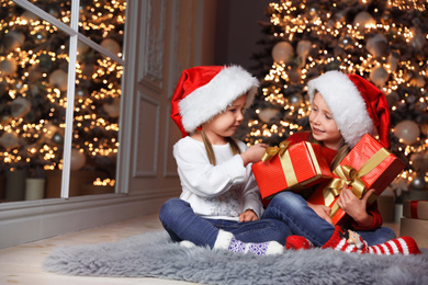 Cute little children with Christmas gifts at home