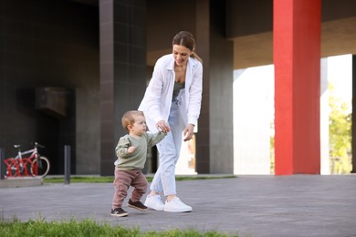 Happy nanny walking with cute little boy outdoors