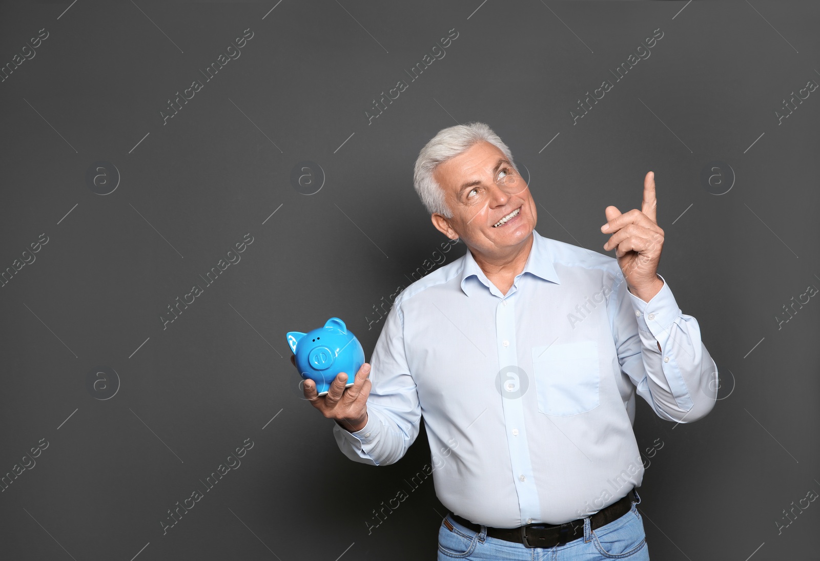 Photo of Mature man with piggy bank on grey background. Space for text