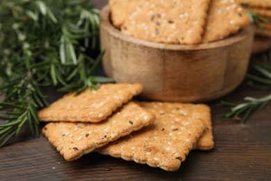 Photo of Cereal crackers with flax, sesame seeds and rosemary on wooden table, closeup