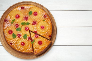 Photo of Delicious cut pineapple pie with cherry and mint on white wooden table, top view. Space for text