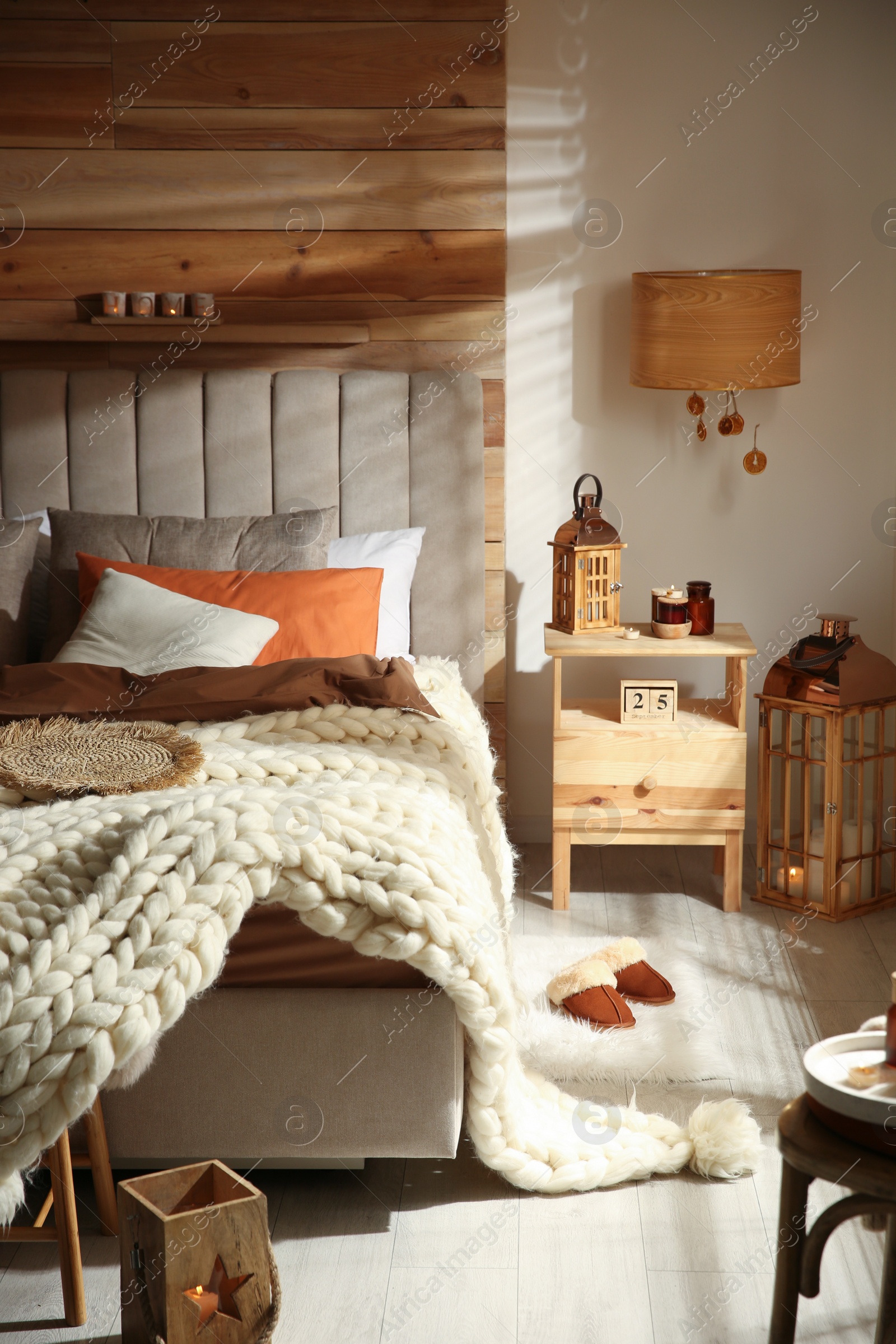 Photo of Cozy bedroom interior with knitted blanket and cushions