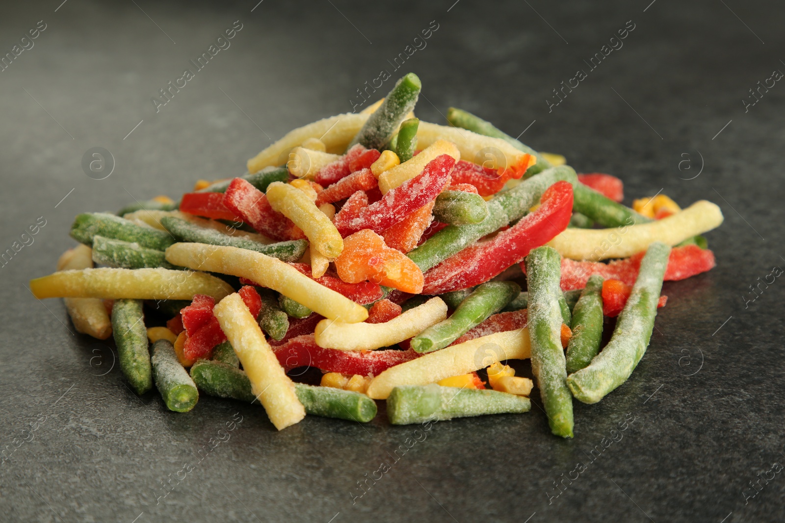 Photo of Mix of different frozen vegetables on gray table, closeup