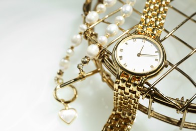 Photo of Stylish presentation of elegant wristwatch and pearl necklace on white background, closeup