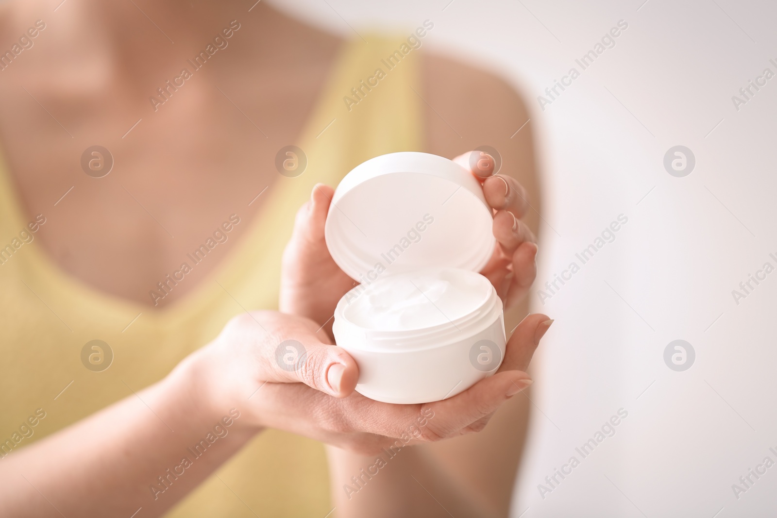 Photo of Young woman holding jar with hand cream, closeup