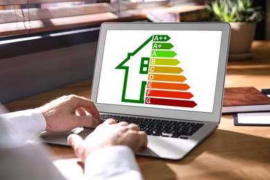 Image of Energy efficiency. Man using laptop with colorful rating on display at table, closeup