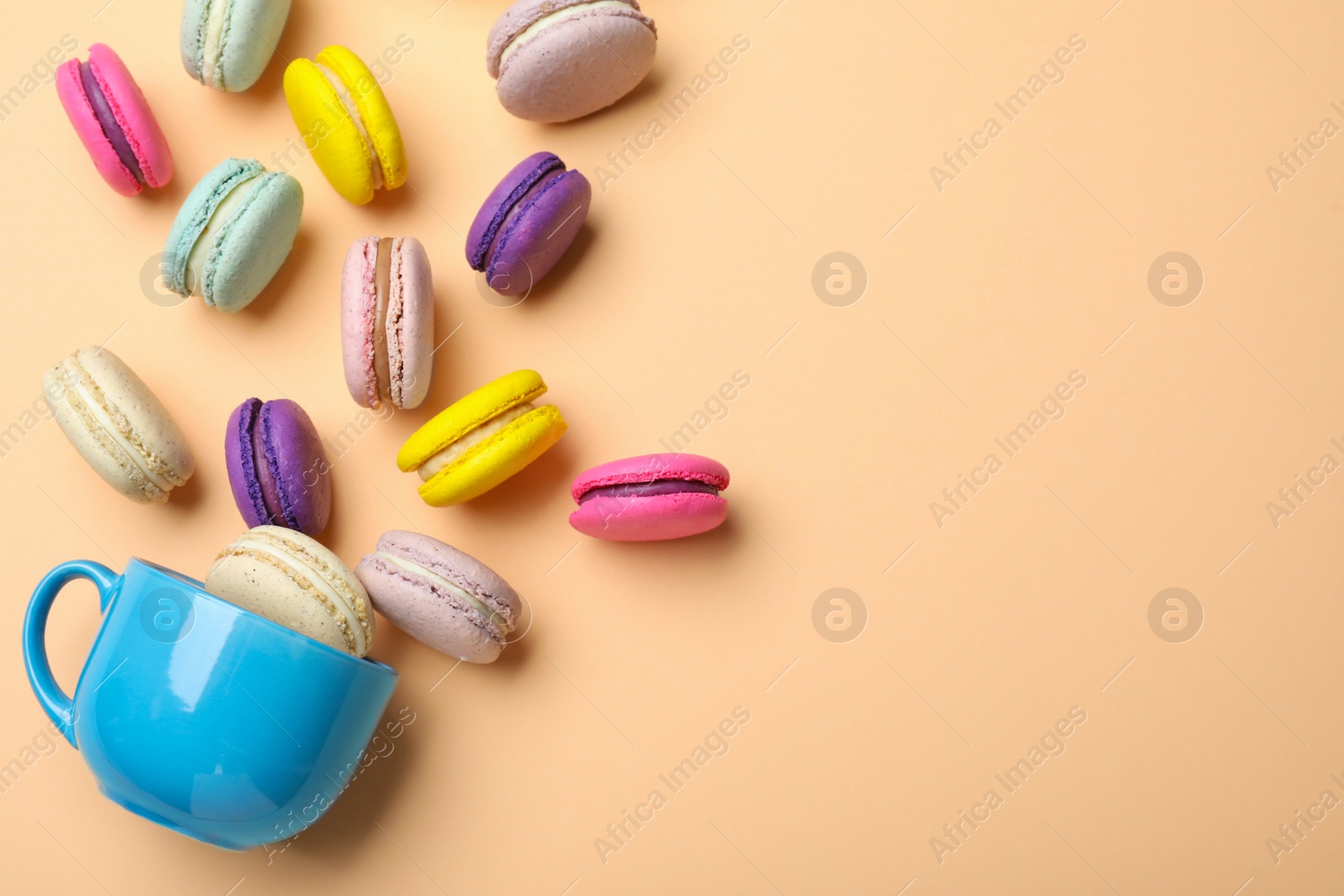Photo of Delicious colorful macarons and cup on beige background, flat lay. Space for text