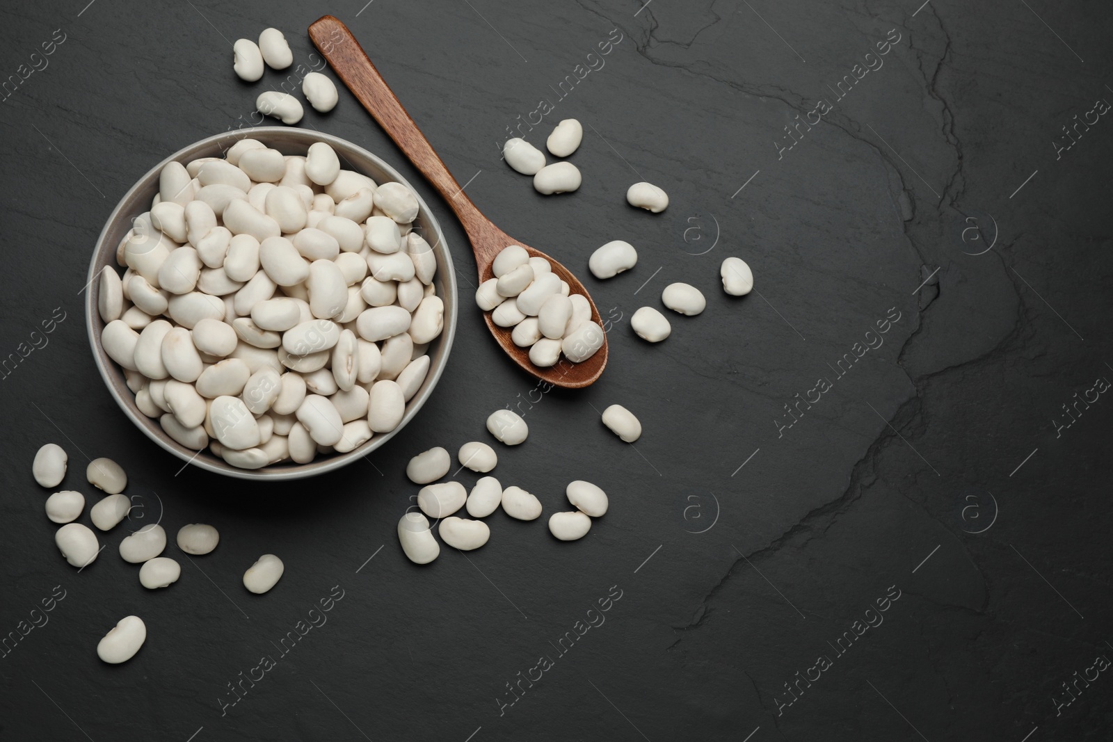 Photo of Raw white beans on black table, flat lay. Space for text