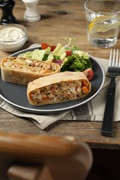 Photo of Pieces of tasty strudel with chicken, vegetables and salad on wooden table