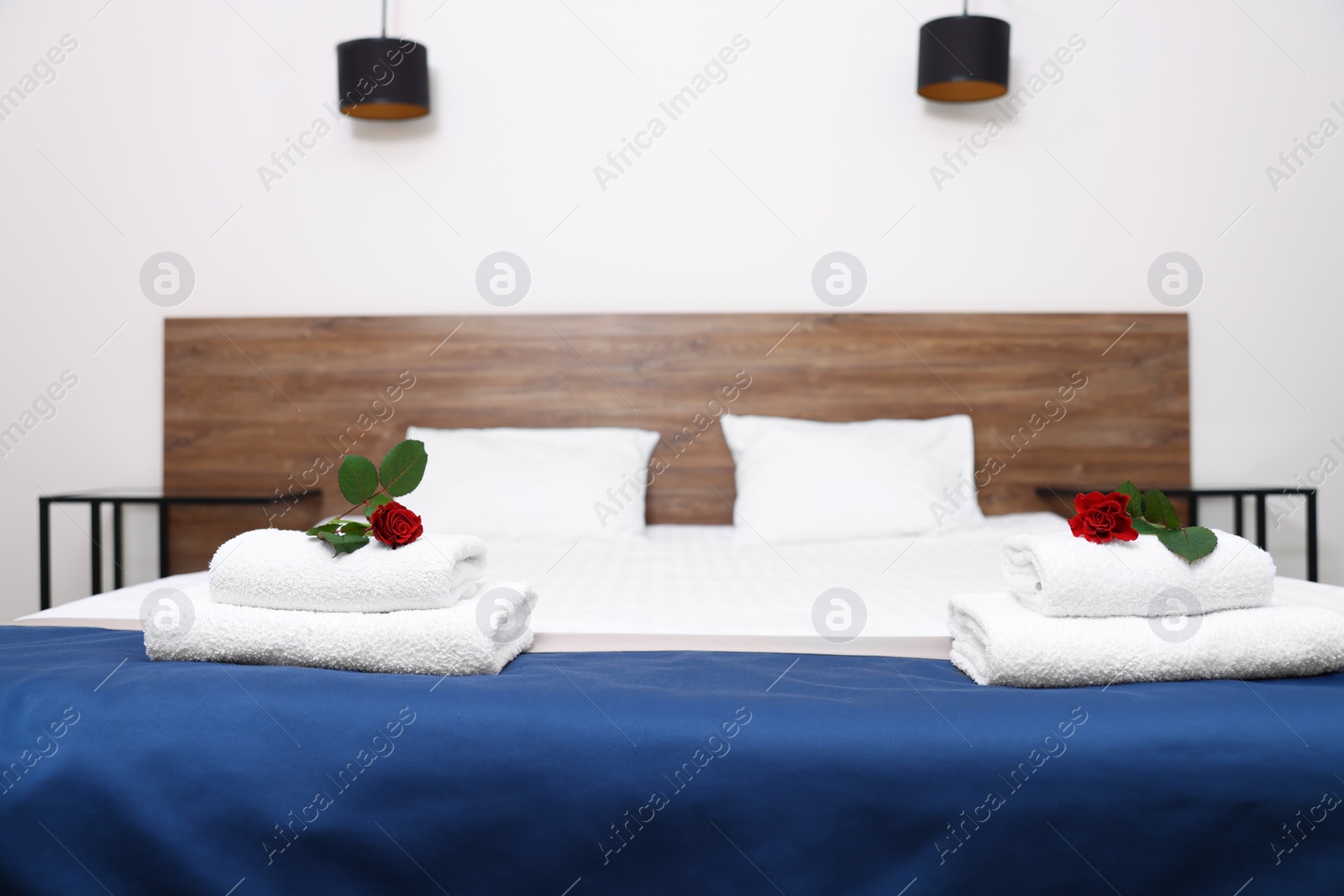Photo of Clean folded towels with flowers on bed in hotel room