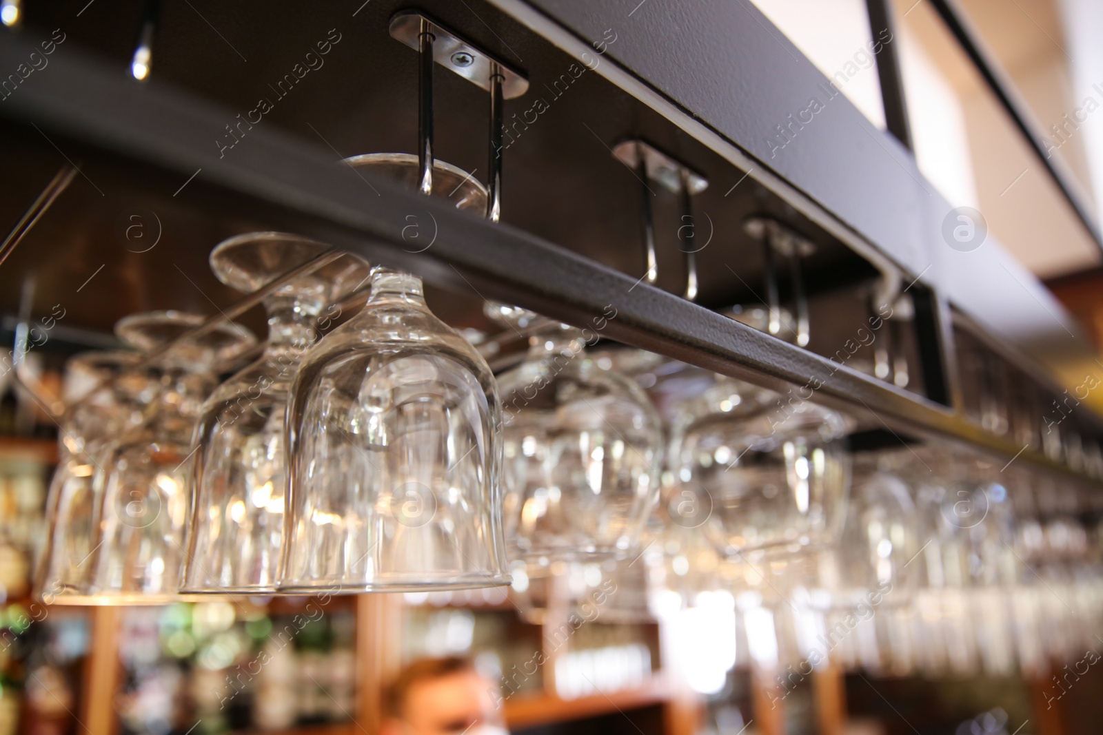 Photo of Many clean glasses on metal rack in restaurant