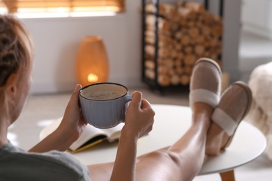 Photo of Woman with cup of aromatic coffee relaxing at home, closeup