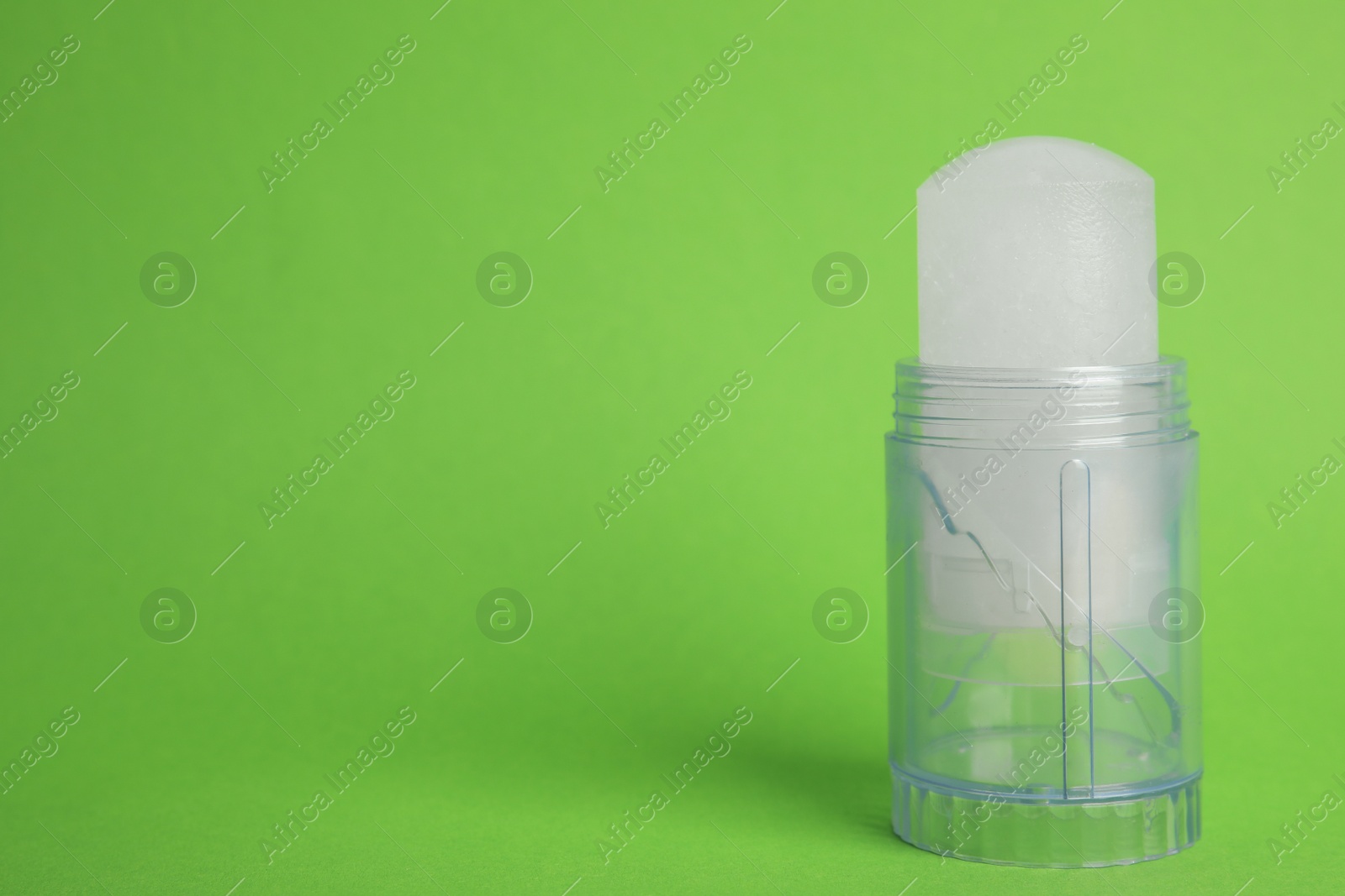 Photo of Natural crystal alum stick deodorant on green background. Space for text