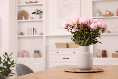 Photo of Vase with pink peonies on wooden table in dining room. Space for text