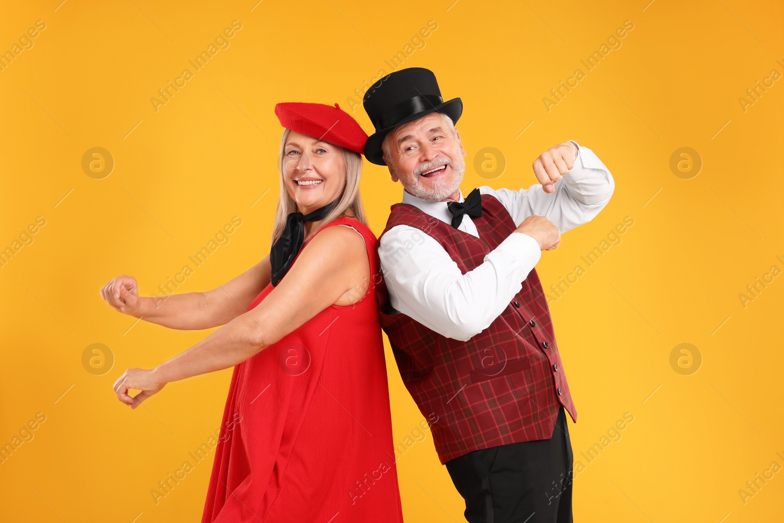 Photo of Senior couple dancing together on orange background