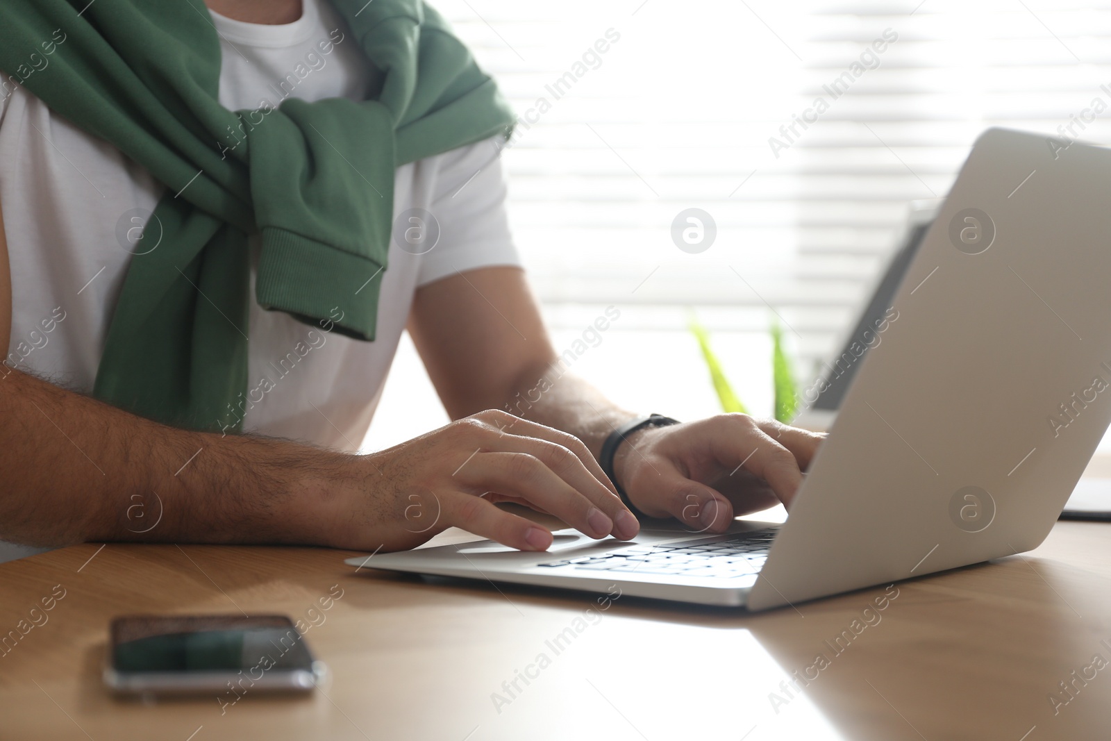 Photo of Freelancer working on laptop at table indoors, closeup