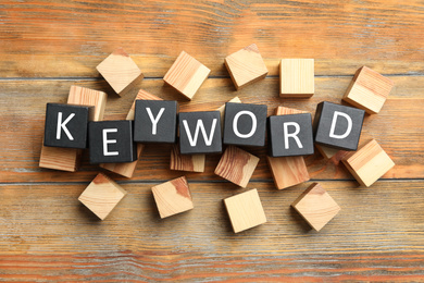 Cubes with word KEYWORD on wooden background, flat lay