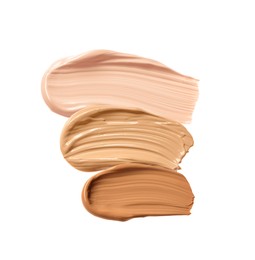 Different shades of liquid skin foundation on white background, top view