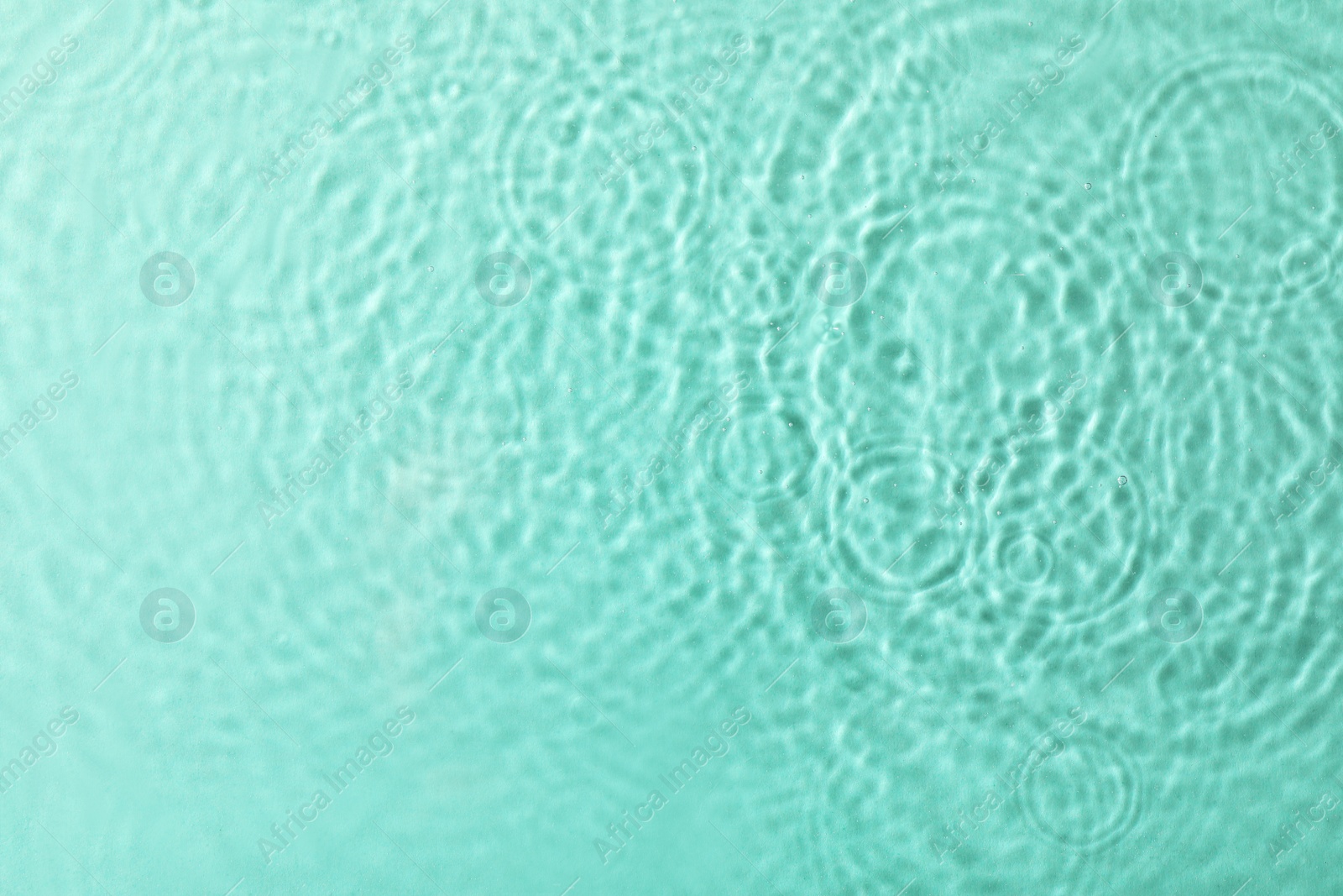 Photo of Clear water with rippled surface on turquoise background, top view