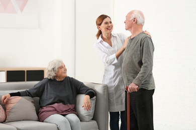 Elderly spouses with female caregiver in living room