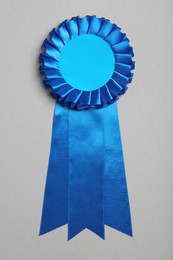 Photo of Blue award ribbon on grey background, top view