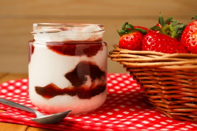 Photo of Tasty yoghurt with jam and strawberries on wooden table, closeup