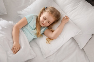 Portrait of cute little girl sleeping in large bed, above view