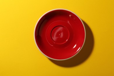 Photo of One clean plate on yellow background, top view. Ceramic dinnerware