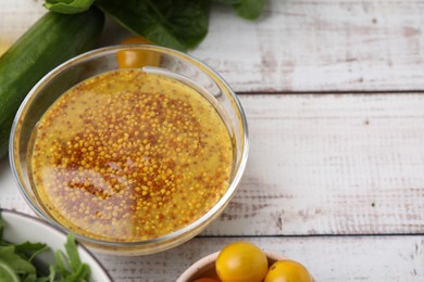 Photo of Tasty vinegar based sauce (Vinaigrette) in bowl and products on wooden rustic table, above view. Space for text