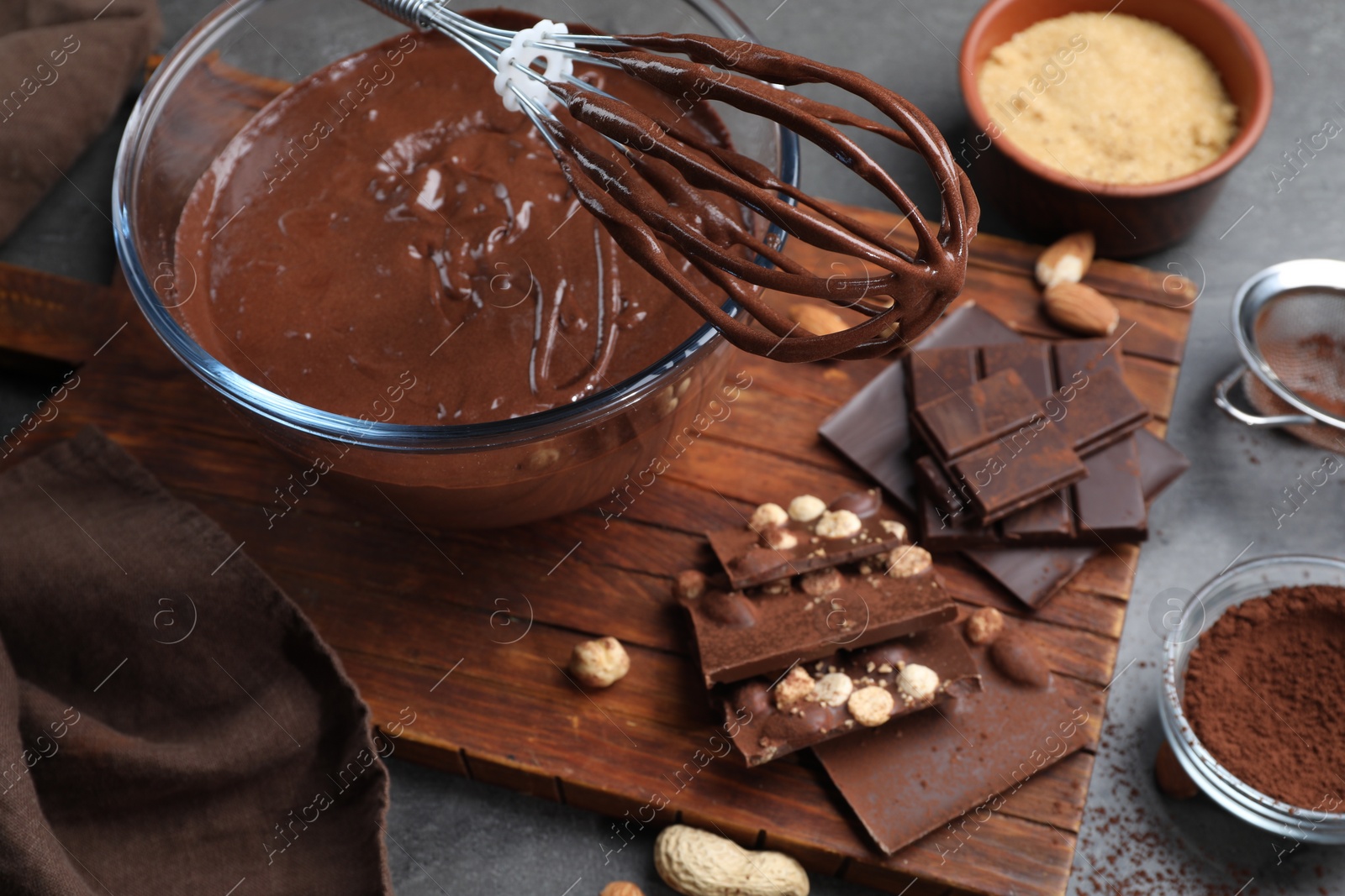 Photo of Bowl of chocolate cream, whisk and ingredients on table, closeup