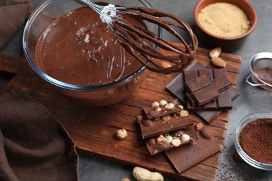 Photo of Bowl of chocolate cream, whisk and ingredients on table, closeup