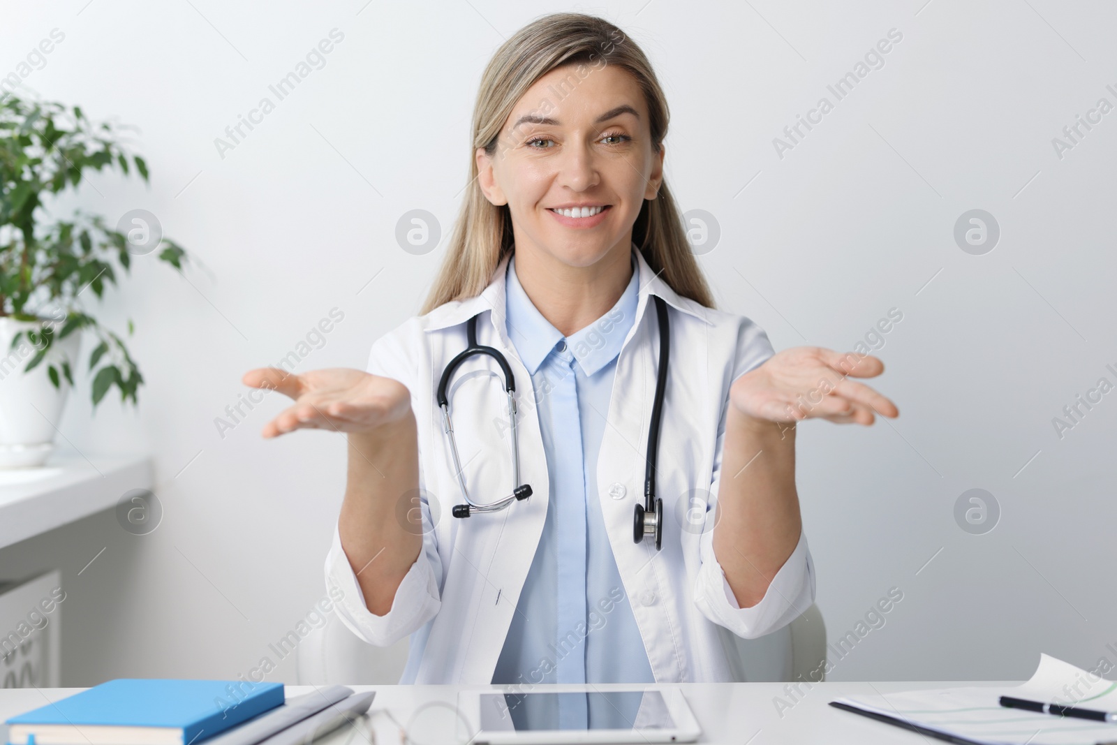 Photo of Portrait of happy doctor with stethoscope at white table in hospital