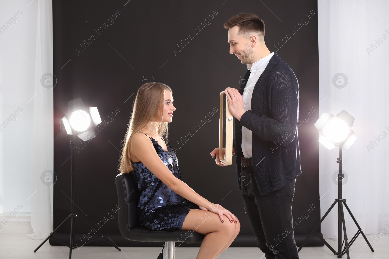 Photo of Professional makeup artist working with beautiful young woman in photo studio