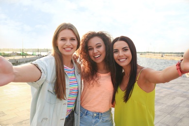 Photo of Happy young women taking selfie outdoors on sunny day