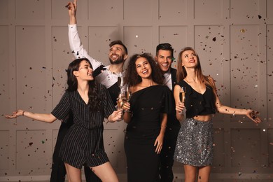 Photo of Happy friends with glasses of sparkling wine celebrating New Year indoors