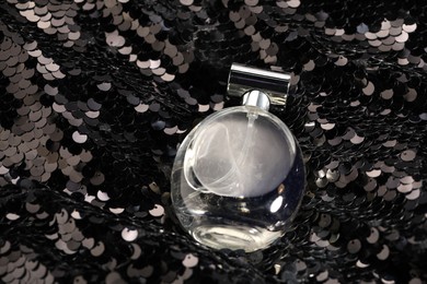 Luxury perfume in bottle on fabric with shiny sequins