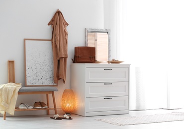 Photo of Modern hallway interior with shoe storage bench and chest of drawers. Space for text