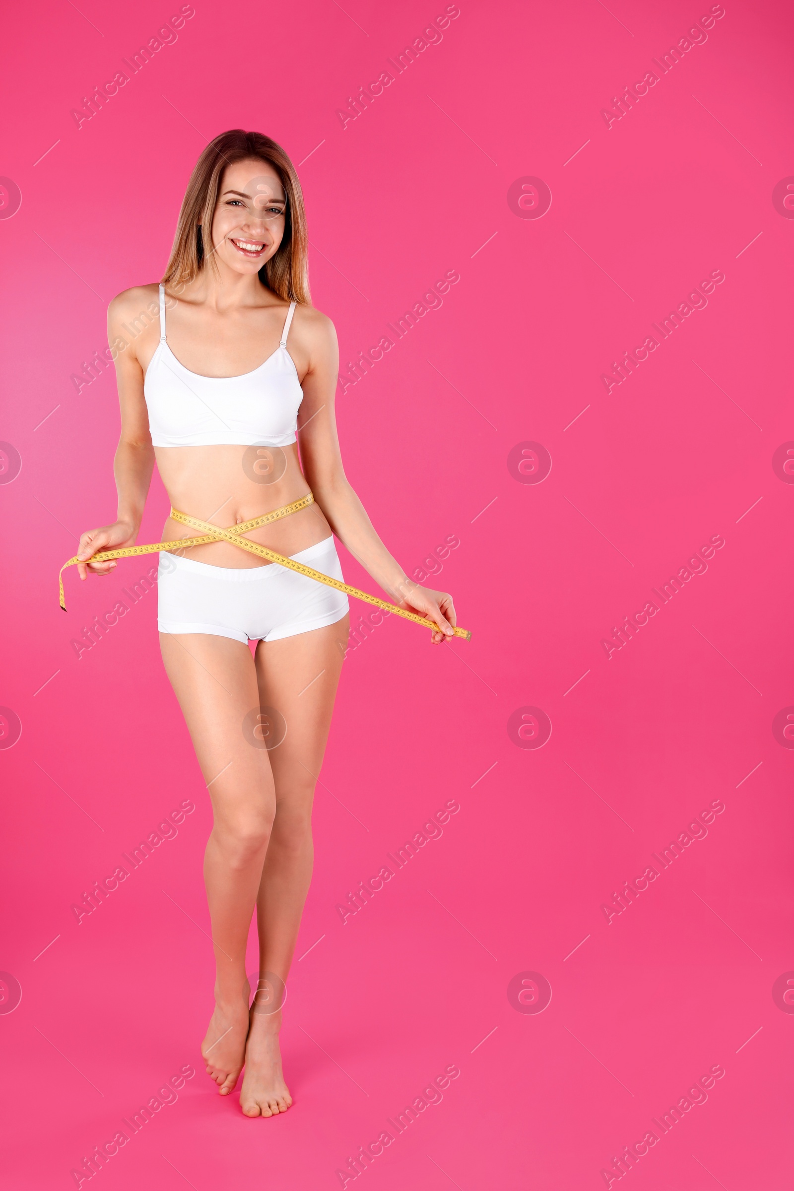 Photo of Slim woman measuring her waist on color background, space for text. Perfect body