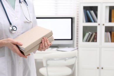Doctor holding books indoors, closeup with space for text. Medical education