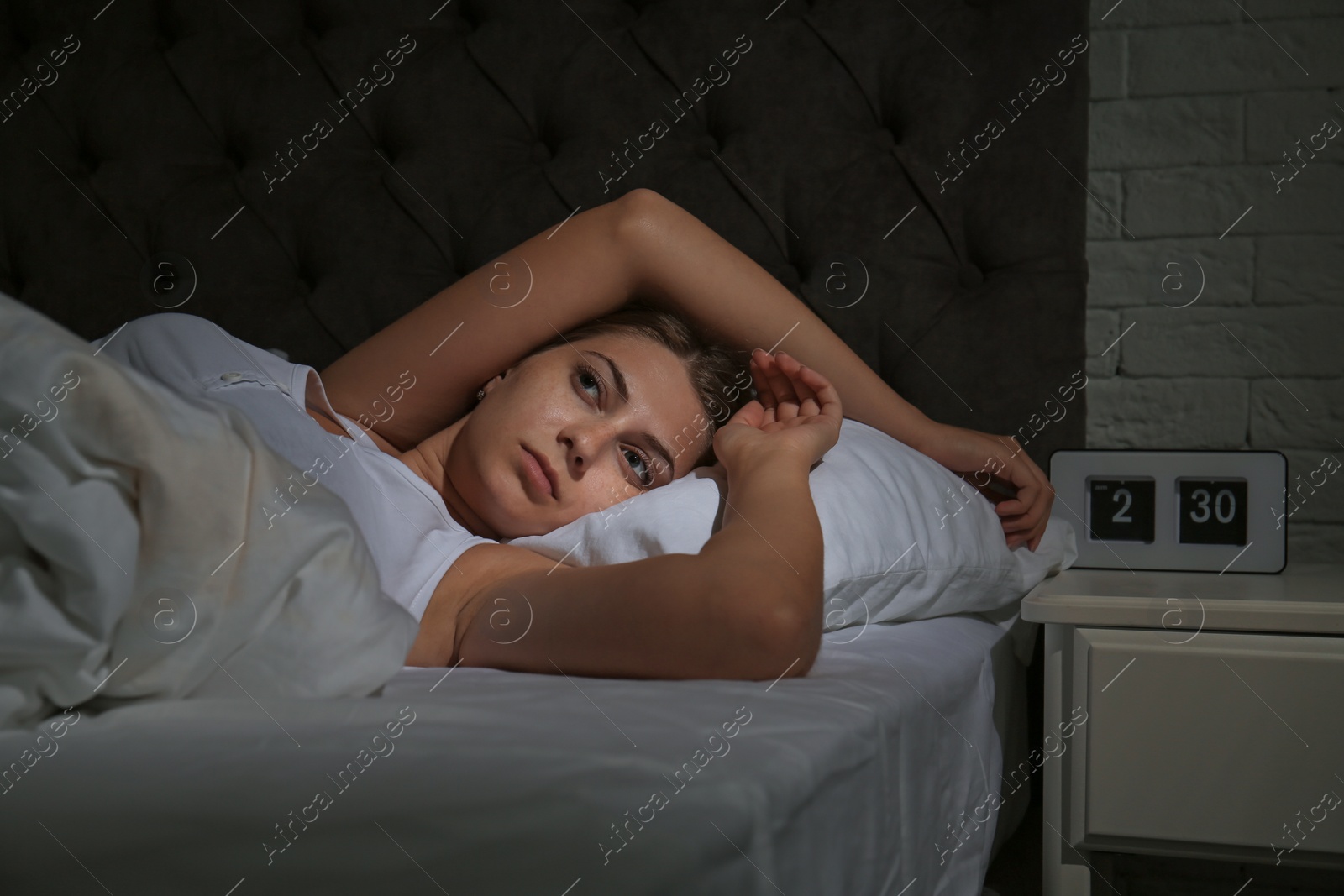 Photo of Young woman suffering from insomnia in bed at home