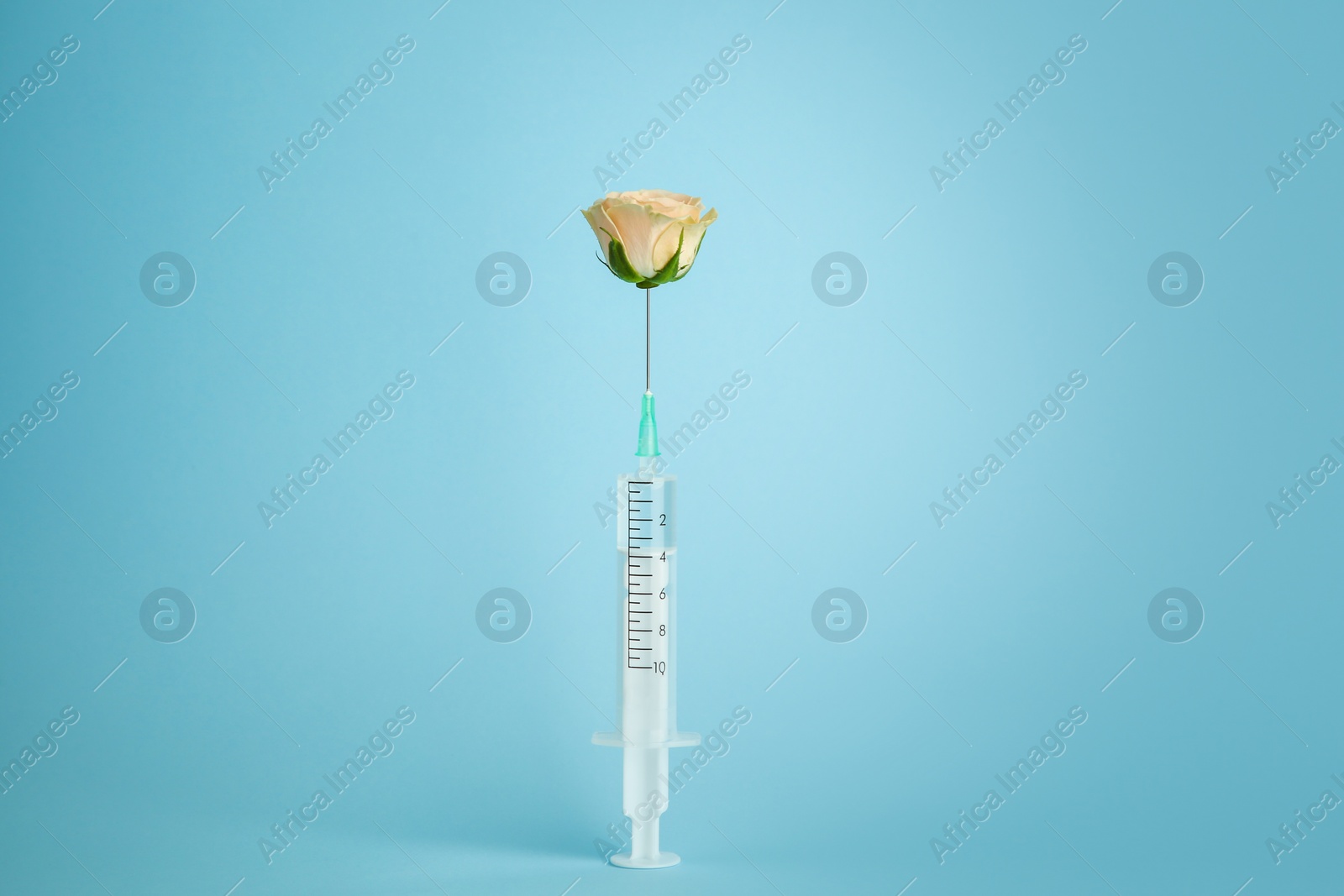 Photo of Medical syringe and beautiful rose on light blue background