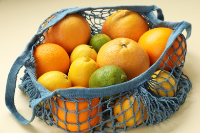 String bag with different fruits on beige background, closeup