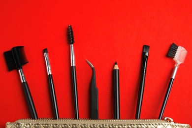 Set of professional eyebrow tools on red background, flat lay